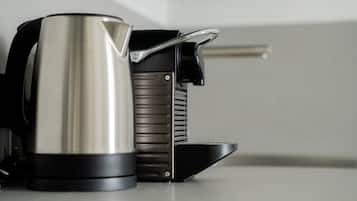 Ein Edelstahl-Wasserkocher und eine schwarze elektrische Kaffeemaschine auf einer Arbeitsfläche.