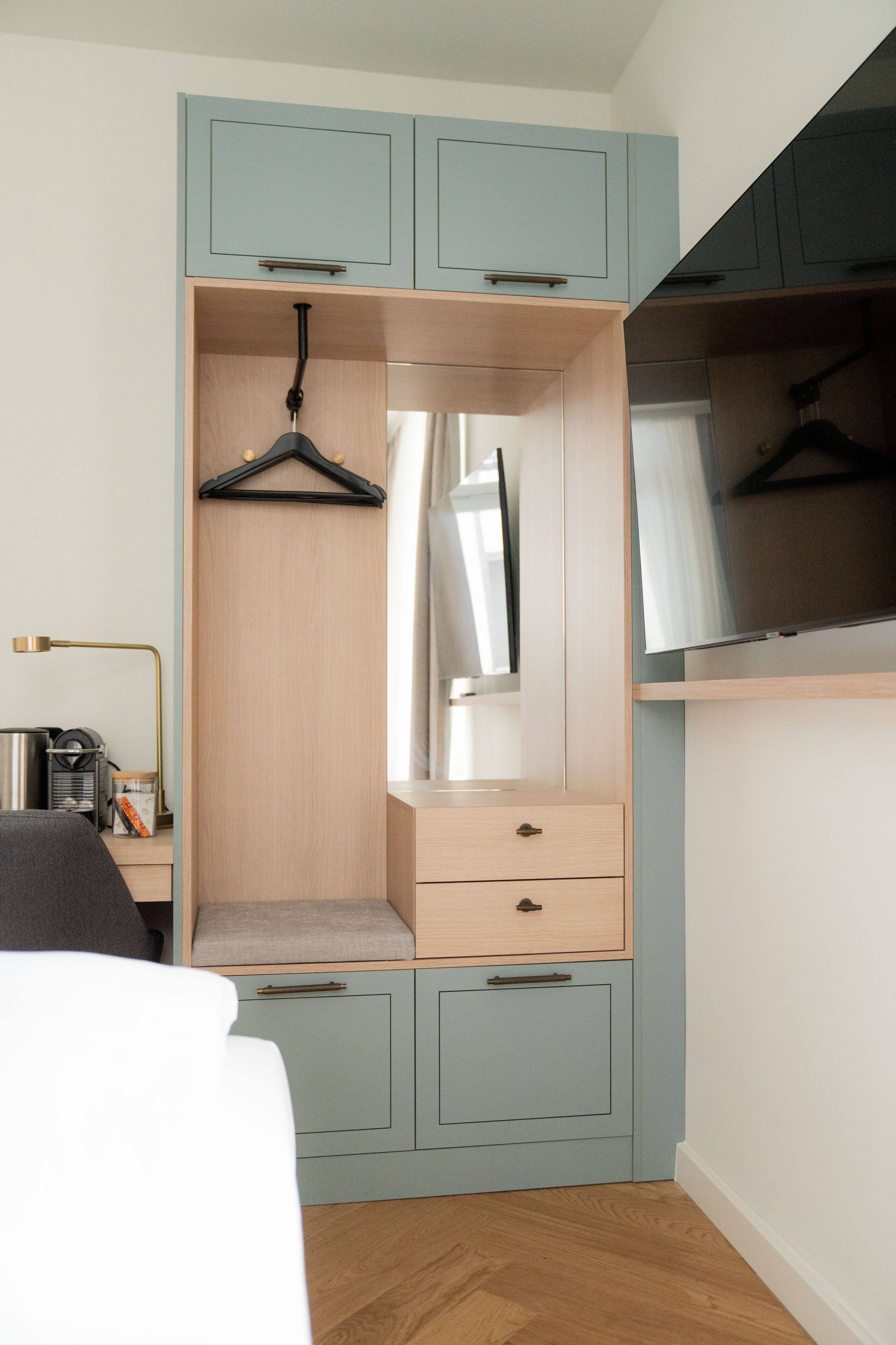 A bedroom with a bed, a wardrobe with a mirror, and a desk with a lamp.