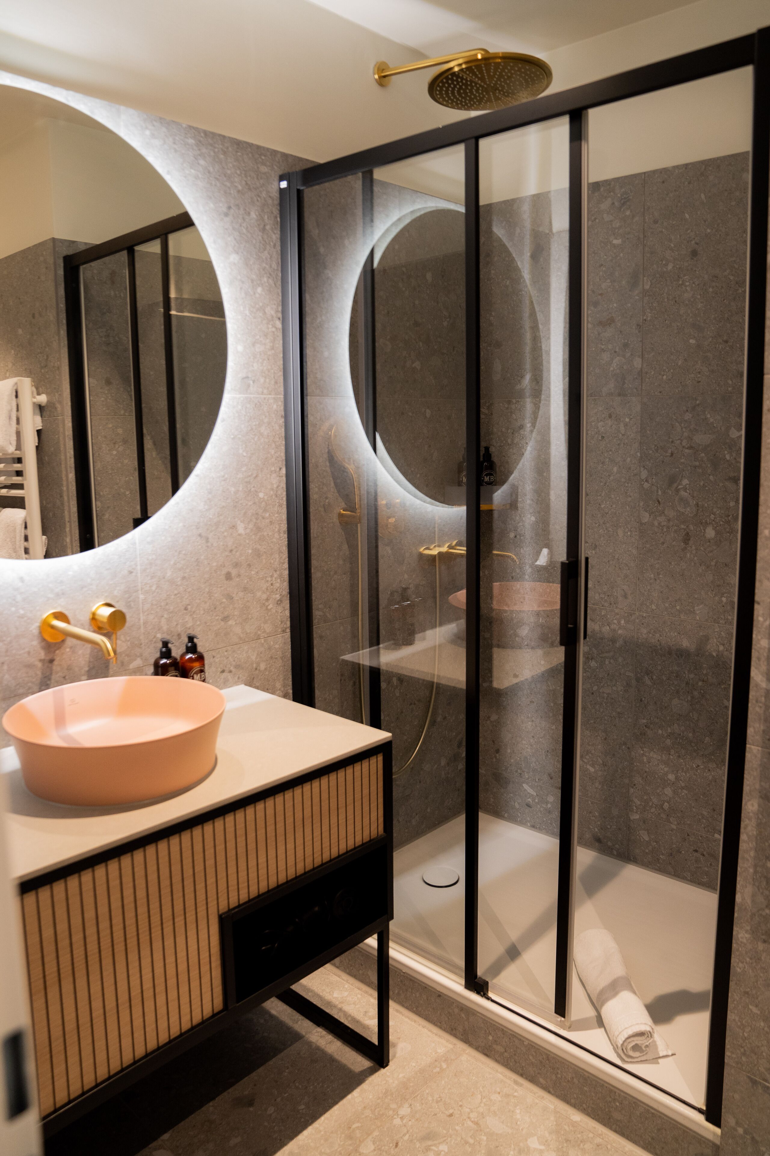 Une salle de bain moderne avec un grand lavabo ovale, une douche à parois de verre et un porte-serviettes.