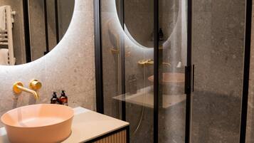 Une salle de bain moderne avec un grand lavabo ovale, une douche à parois de verre et un porte-serviettes.