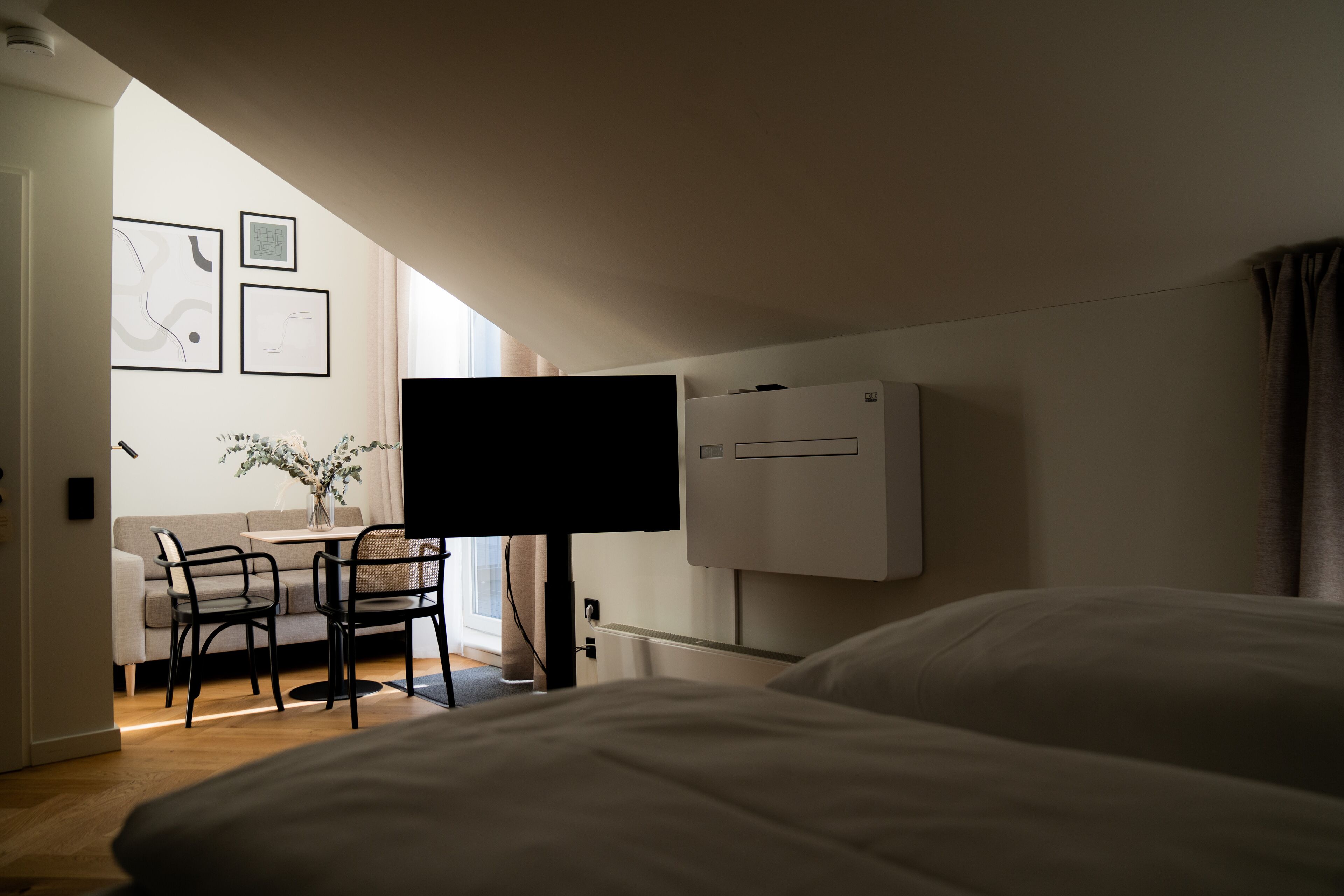 Een hotelkamer met een bed, een bureau met stoelen, een flatscreen-tv en een radiator.