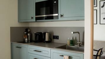 Una cocina con gabinetes azul claro, microondas, cafetera y lavamanos.
