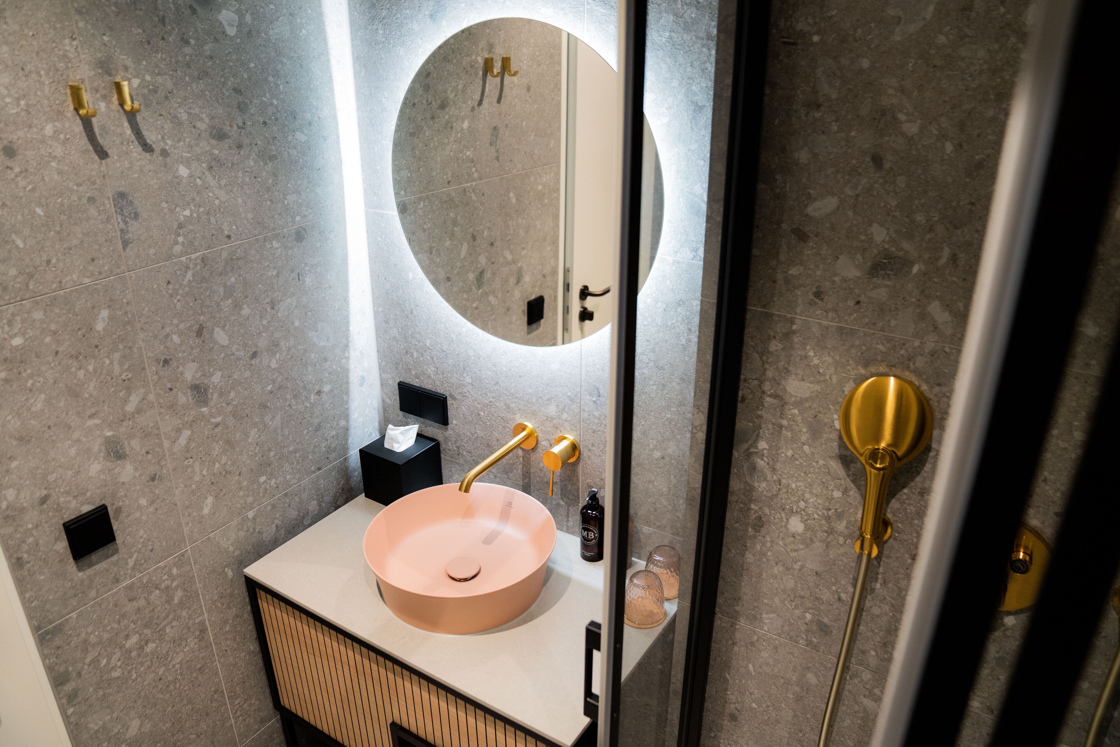 Een moderne badkamer met een ronde wastafel, een spiegel en een handdoekrek.
