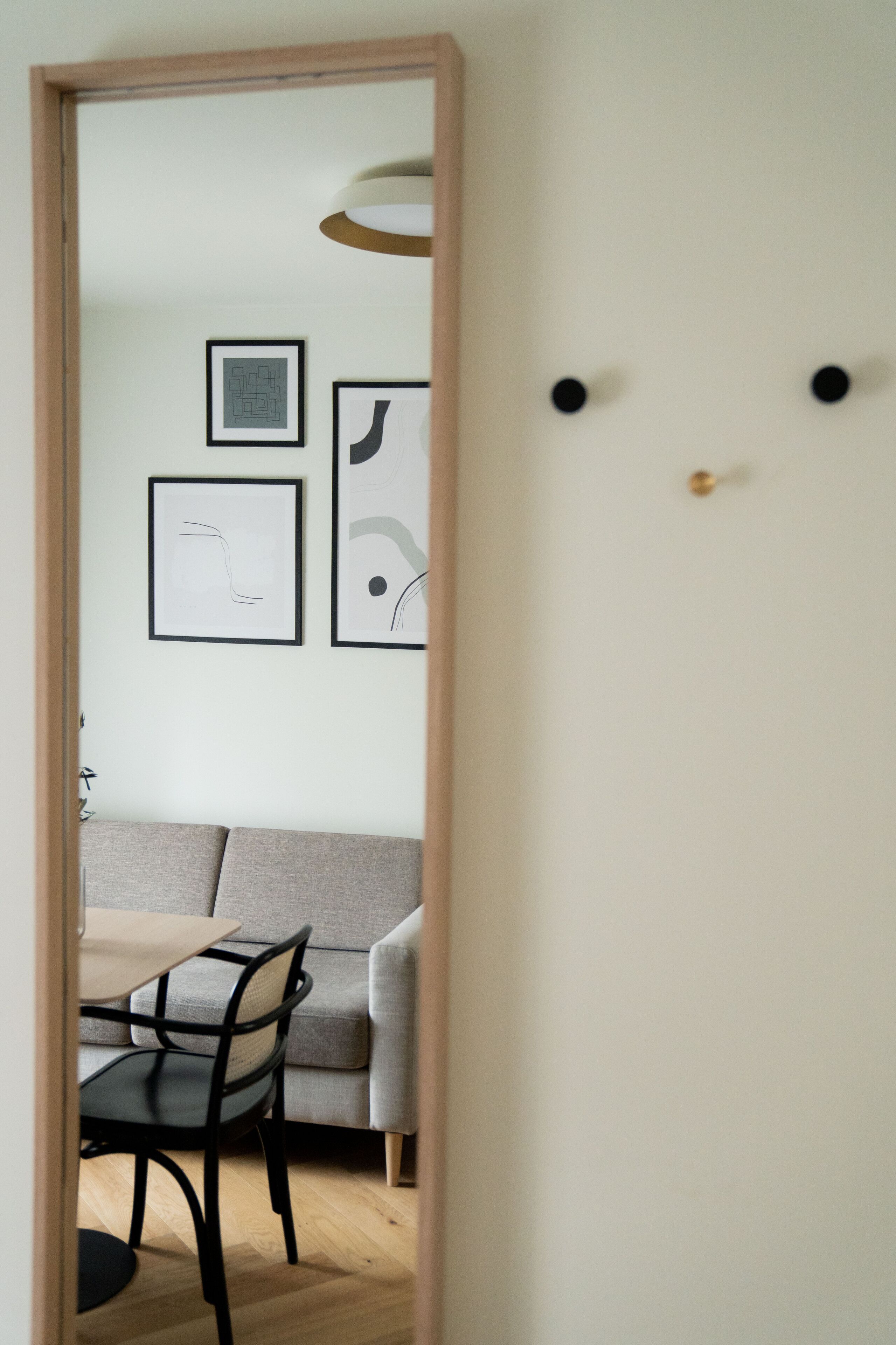 A room with a sofa, a dining table with chairs, and framed artwork on the wall.