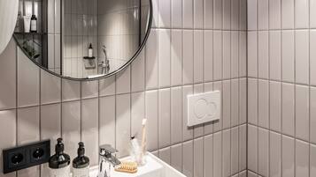 A modern bathroom with a white sink, mirror, and toilet.