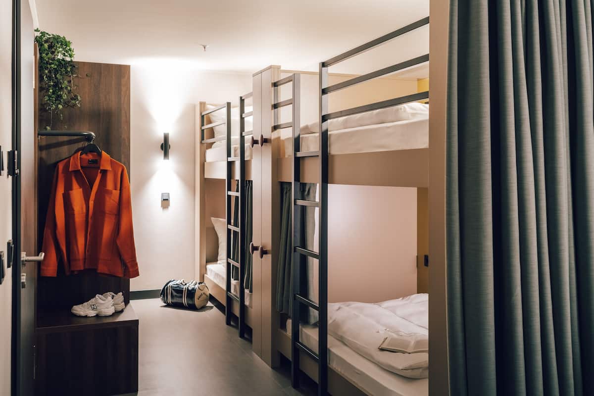 Habitación con literas, un armario, un abrigo colgado y un par de zapatillas.