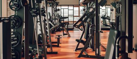 Un gimnasio con equipo de levantamiento de pesas variado, una banca y un suelo de color naranja brillante.