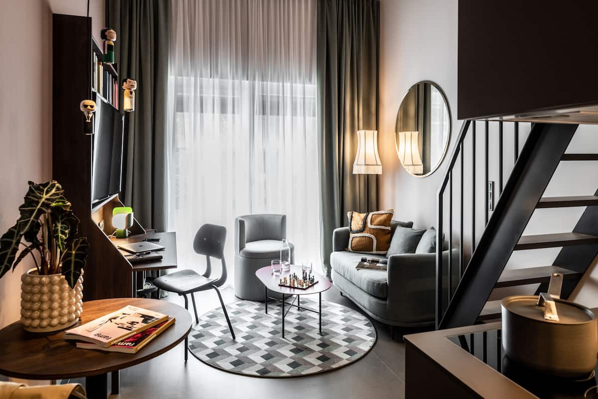 Una sala de estar moderna con un sofá, sillones, una mesa de centro y una estantería.
