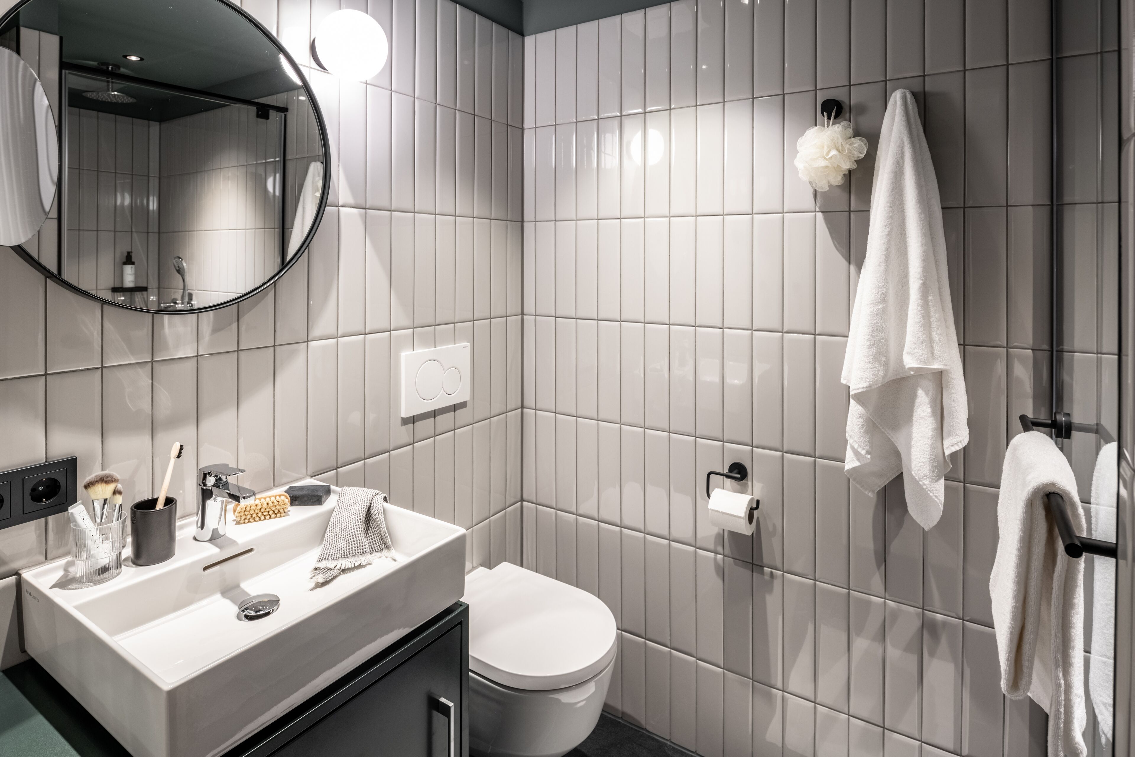 A modern bathroom with a white sink, mirror, toilet, and towel rack.