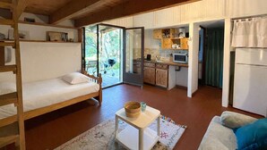 Ein gemütliches Blockhaus mit Holzvertäfelung, einem Stockbett, einer Küchenzeile und einem Essbereich.