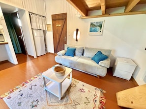 Un salon confortable avec un canapé, une petite table, un tapis et une étagère en bois.