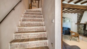 Una scala con gradini in mattoni conduce a una stanza con parete in pietra e camino.