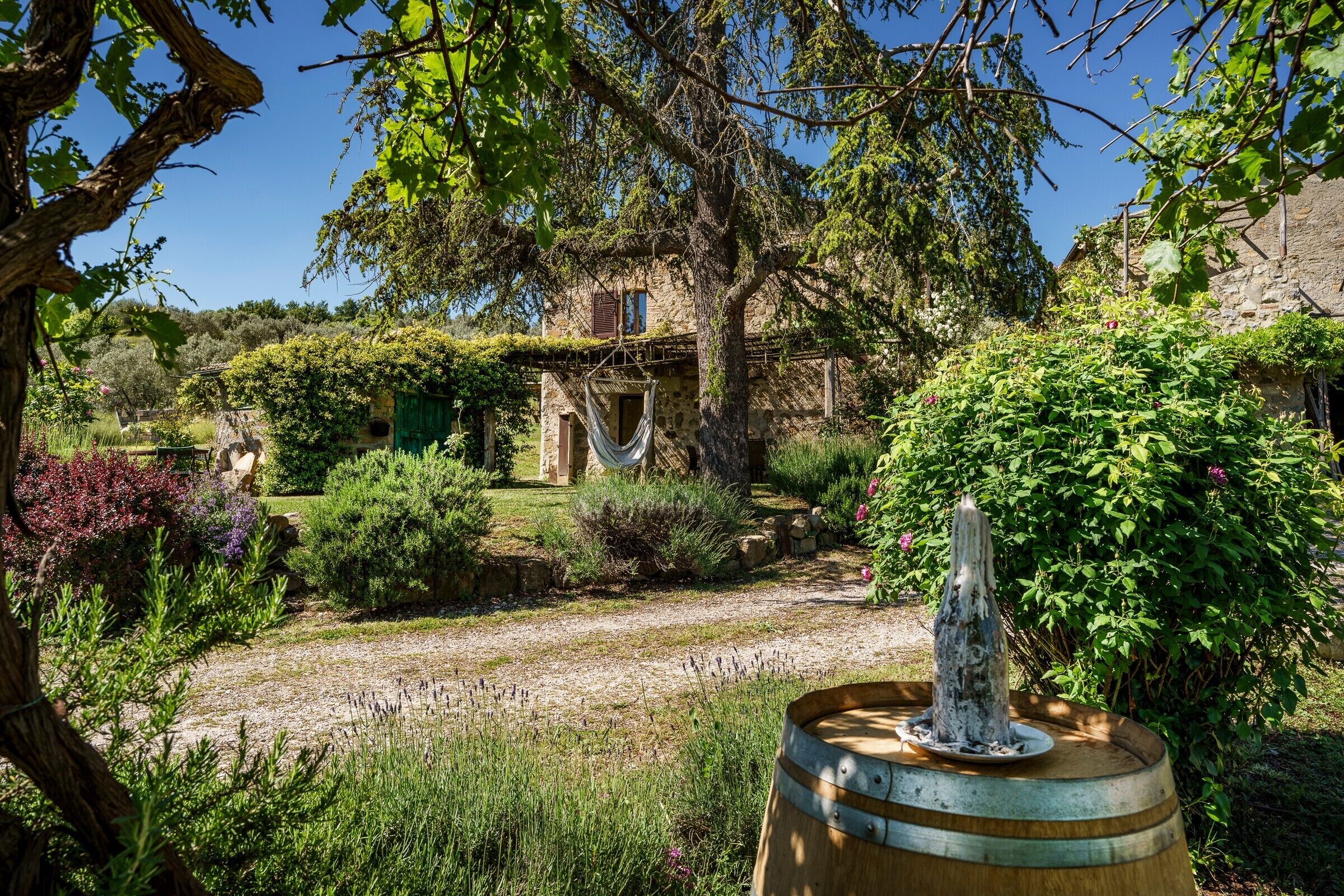 Un bâtiment rustique en pierre, doté d’un jardin, d’un hamac et d’une fontaine.