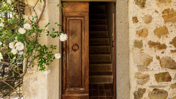 Un edificio in pietra con una porta di legno e una scala che conduce all'interno.