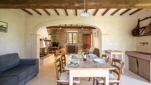 Zona pranzo con tavolo in marmo, sedie di legno e parete in pietra sullo sfondo.