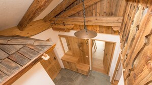 Ein rustikaler Holzraum mit Steinboden, Holzstufen und einer hängenden Leuchte.