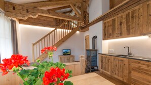 Eine rustikale Küche mit Holzausbau, einer Holztreppe und einem Fernseher auf einem Holzständer.
