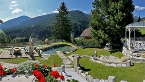 A garden with a gazebo, a fountain, and a pool. - Apartment Piz da Peres - Geiselsberg with Mountain View, Pool, Sauna, Wi-Fi & Garden (Olang)