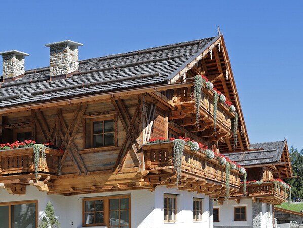 Un chalet traditionnel doté de balcons en bois, de cheminées en pierre et d’un toit à pente.