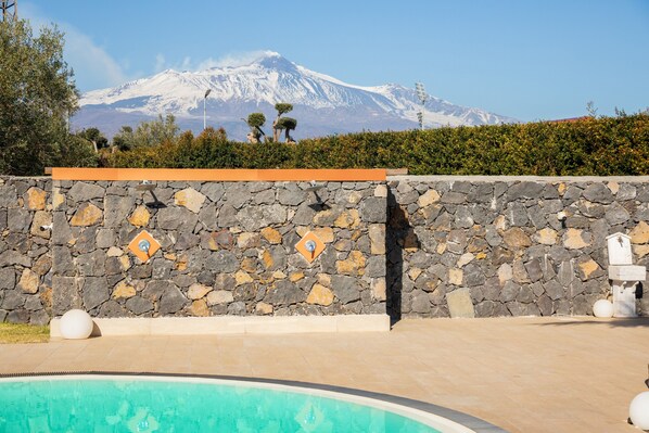 A swimming pool with a stone wall and a view of a snow-capped mountain.