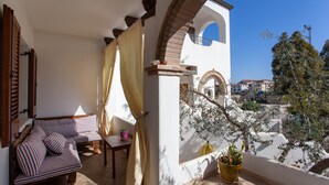 A balcony with a sofa, a table, and potted plants. - Holiday Apartment "Casa Antonella" with Garden, Balcony & Air Conditioning (Orosei)