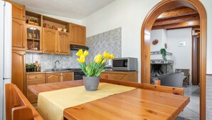 Eine Küche mit Holzausstattung, einem Esstisch mit gelber Tischdecke und einem Topf mit gelben Blumen.