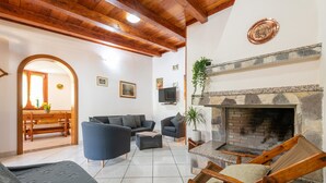 Ein Wohnzimmer mit Kamin, Sofas, einem Fernseher und einem Essbereich mit Tisch und Stühlen.