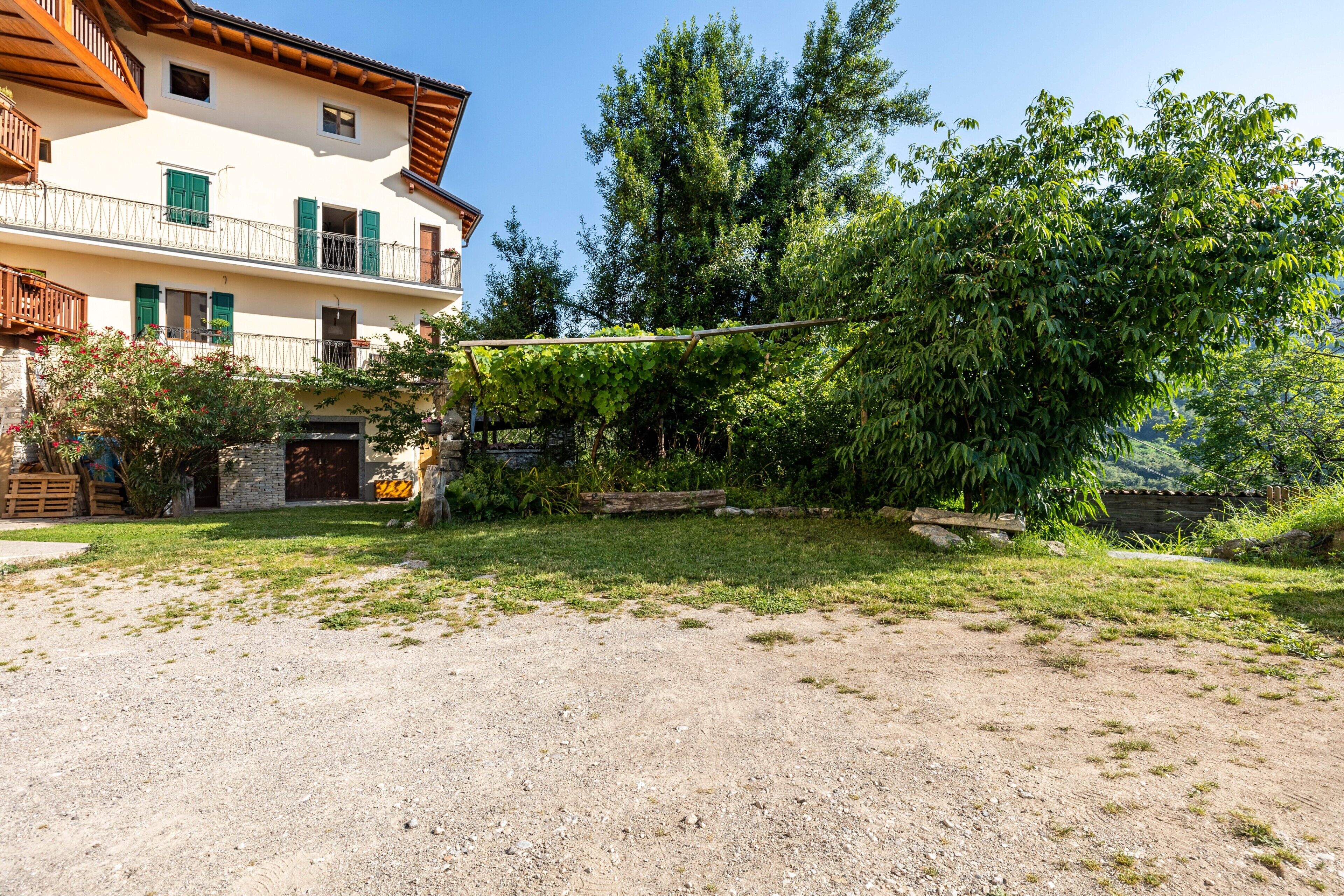 A building with a balcony, a grassy yard, and a tree.