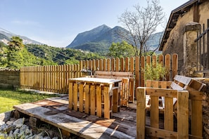 A wooden deck with a table and chairs, surrounded by a wooden fence, with a mountain in the background. - Residence Lena App 2 (Pranzo)