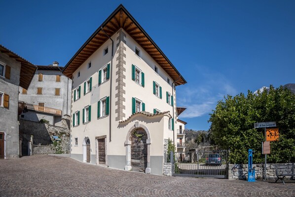 A building with a stone facade, multiple windows with shutters, and a cobblestone street. - Residence Lena App 2 (Pranzo)