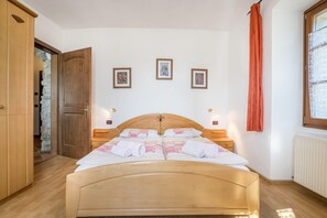 Un dormitorio con una cama de madera, una pared de piedra y una ventana con cortina.