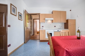 Una cocina compacta con armarios de madera, una estufa blanca y un mantel rojo.