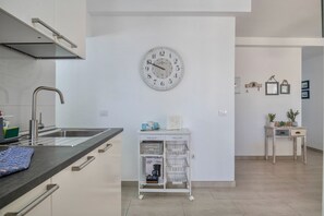 A modern kitchen with a clock, a sink, a cabinet, and a small table with plants.