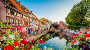 Un canal bordé d’immeubles aux couleurs vives d’un côté et traversé par un pont au milieu.