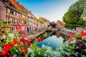 A canal with colorful buildings on one side and a bridge in the middle.