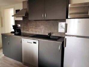 Modern kitchen with a sleek design, featuring a stainless steel refrigerator, dishwasher, double sink, and electric kettle.