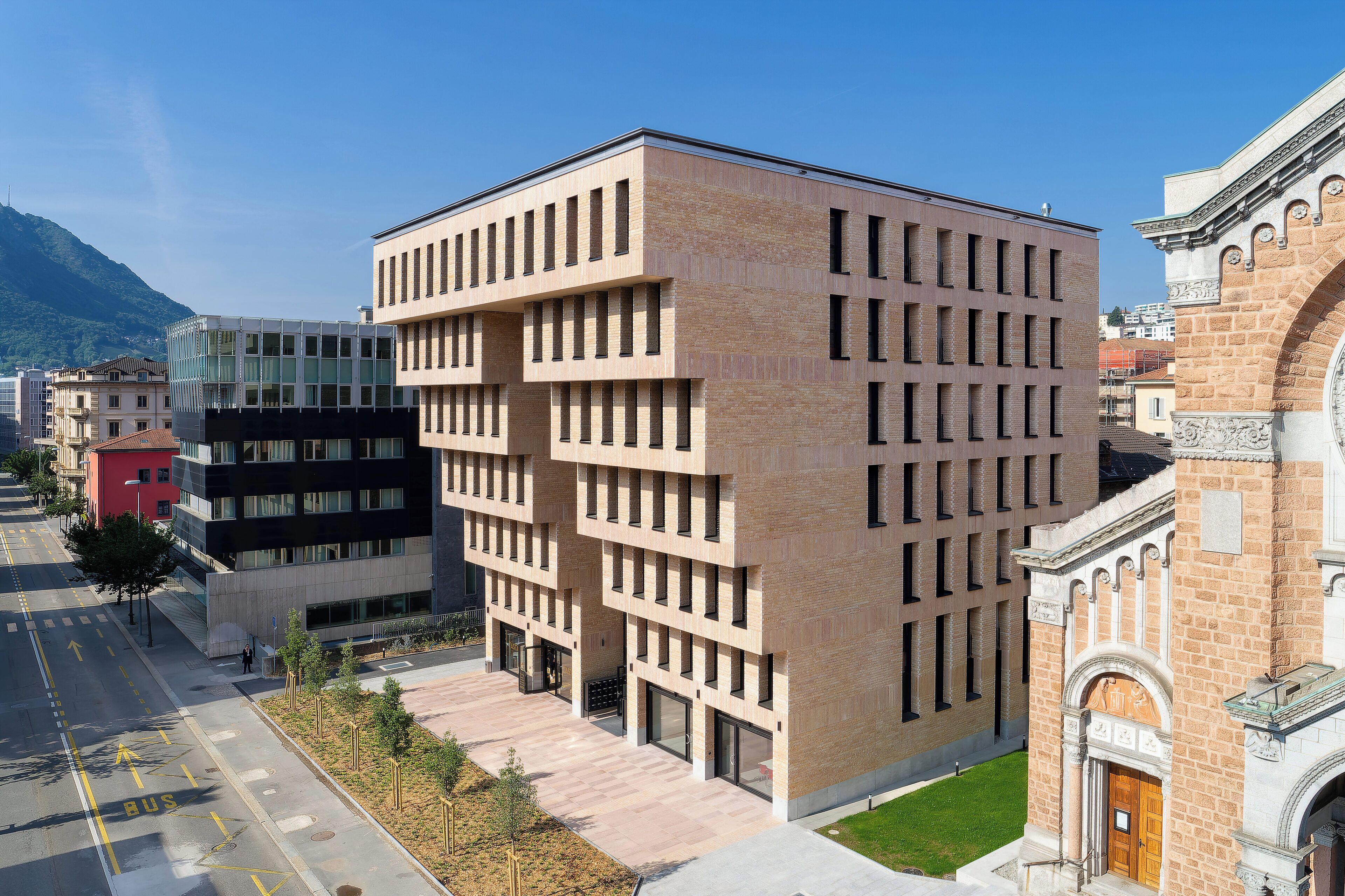 Un bâtiment moderne doté d’une façade à motifs géométriques de fenêtres et d’une cour intérieure.