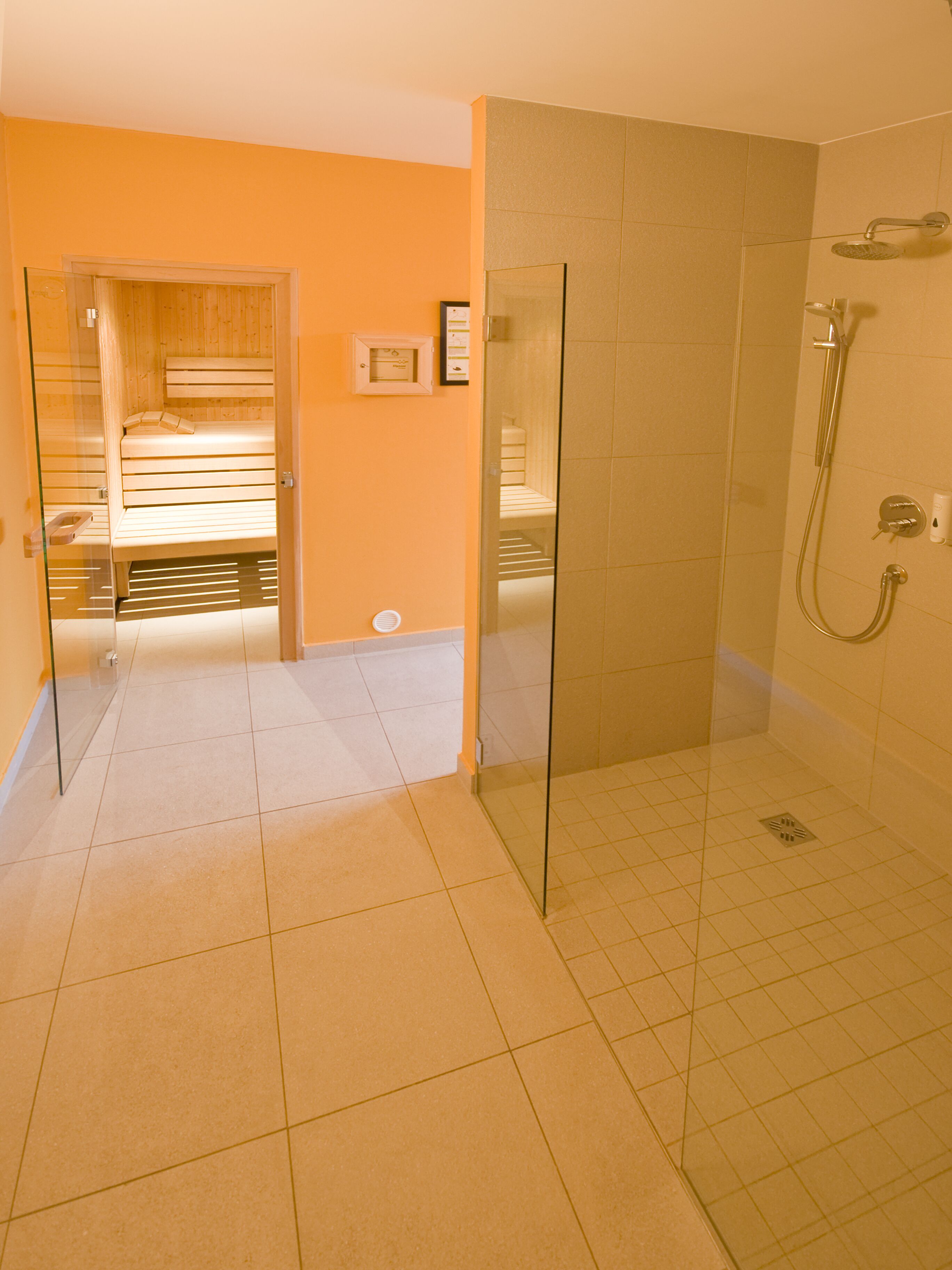 Une salle de bain avec une douche à parois de verre, un banc en bois et un sol carrelé.