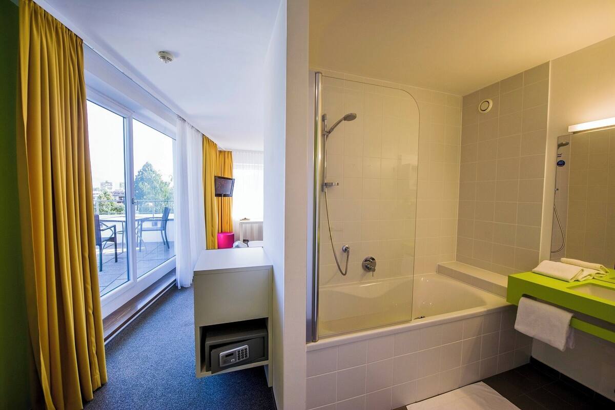 A modern bathroom with a glass-enclosed shower, a standalone bathtub, and a vanity with a green countertop.