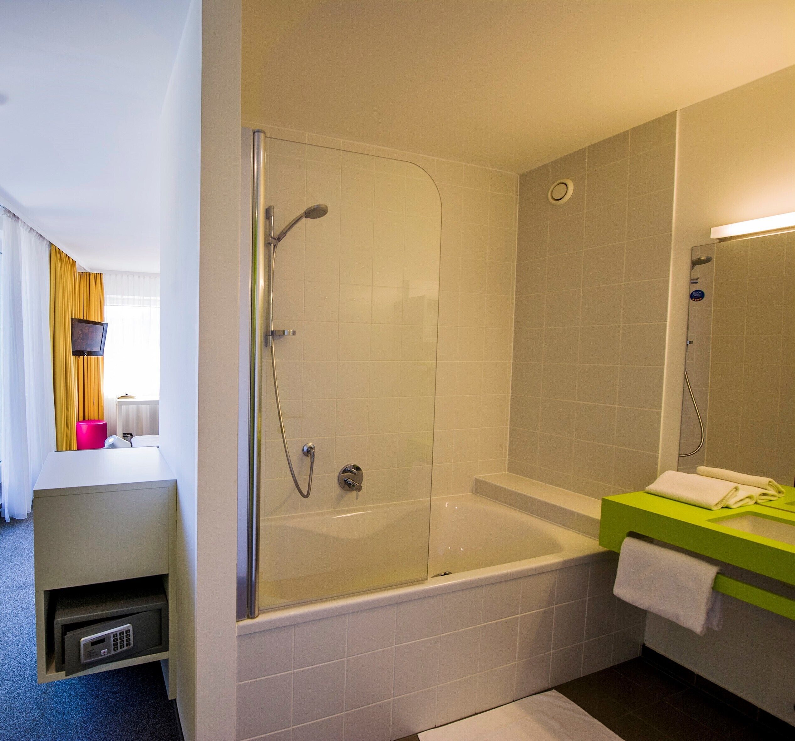 A modern bathroom with a glass-enclosed shower, a freestanding bathtub, and a vanity with a green countertop.