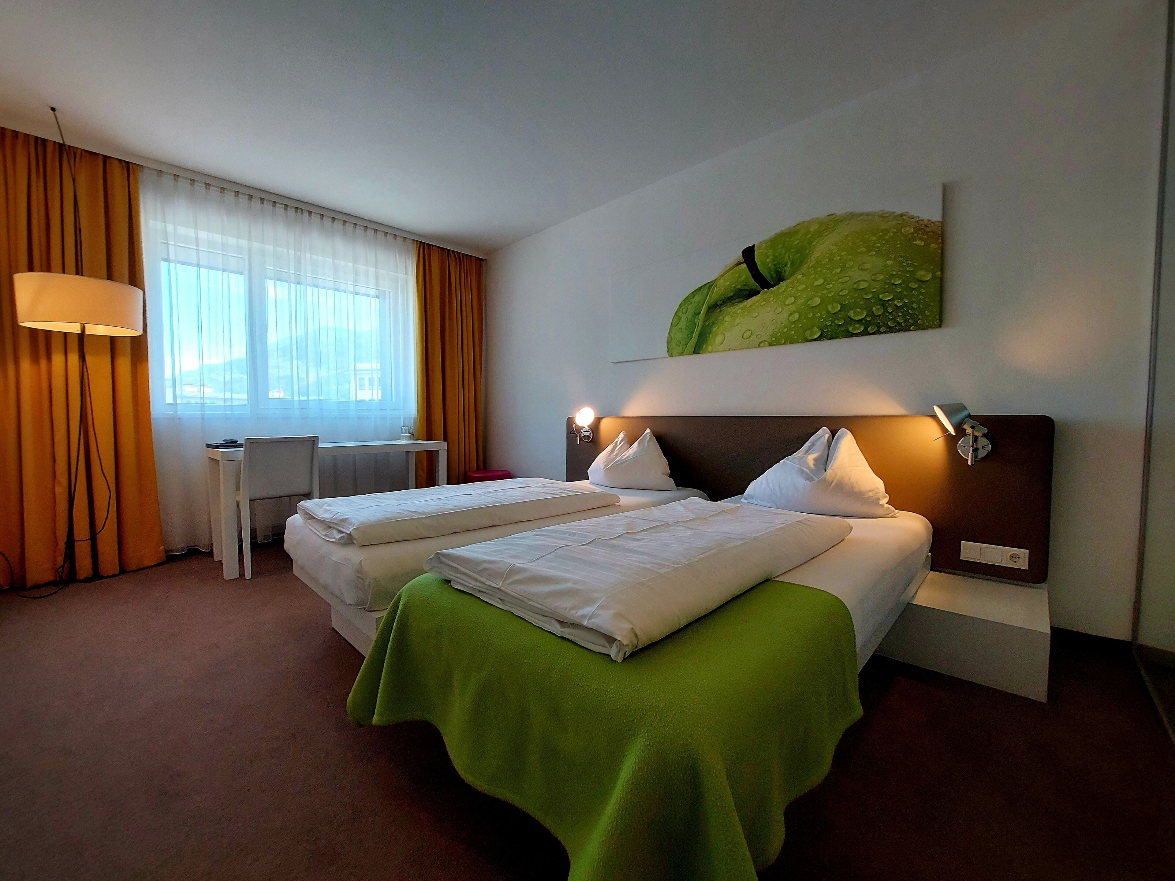 A hotel room with two beds, a desk, and a chair.