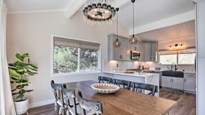 Een moderne keuken met een houten eettafel, hanglampen en uitzicht op de omgeving.