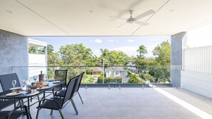Un comedor moderno con barandilla de vidrio que da vista a un barrio residencial.