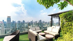 Une terrasse sur le toit, aménagée avec des meubles en osier, une pelouse artificielle verdoyante et offrant une vue sur la ville.