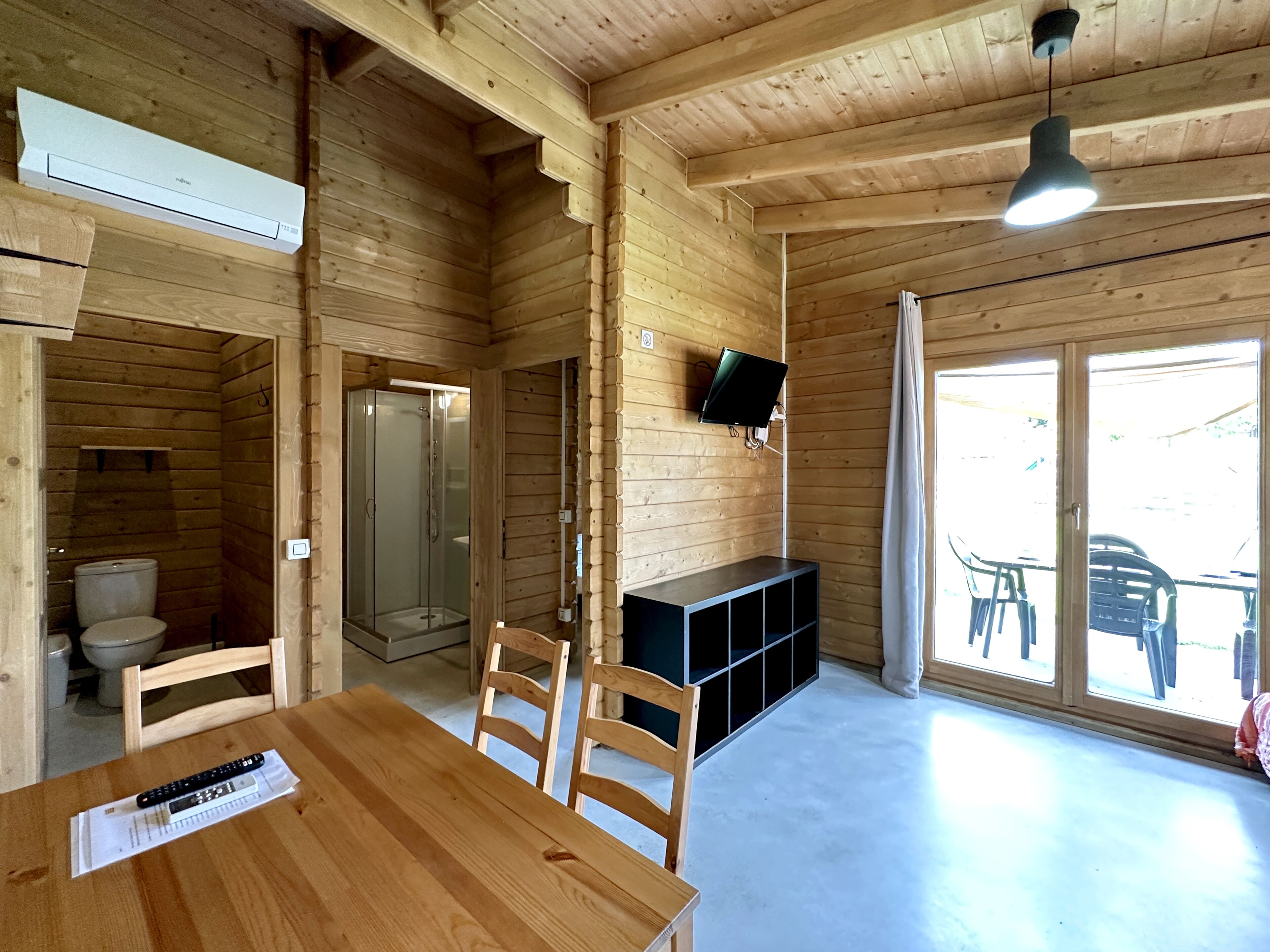 Un interior de madera con una mesa de comedor, sillas, un televisor y una ducha.