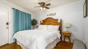 A neatly arranged bedroom with a wooden bed, a ceiling fan, a nightstand with a lamp, and a wall-mounted sign. - Oceanfront Hilton Head Island Condo w/ Pool! (Hilton Head Island)