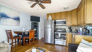 A modern kitchen with wooden cabinets, stainless steel appliances, and a dining area with a table and chairs. - Oceanfront Hilton Head Island Condo w/ Pool! (Hilton Head Island)