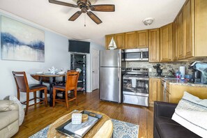 A modern kitchen with wooden cabinets, stainless steel appliances, and a dining area with a table and chairs. - Oceanfront Hilton Head Island Condo w/ Pool! (Hilton Head Island)
