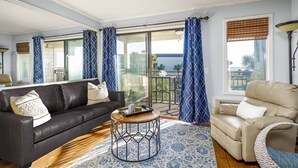 A living room with a dark leather sofa, a beige armchair, and a round coffee table. - Oceanfront Hilton Head Island Condo w/ Pool! (Hilton Head Island)