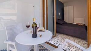 A room with a bed, a table with a bottle and glasses, and a chair. - Neva-Elegant Suite with Balcony in Massa Lubrense center 10 minutes from Sorrento (Massa Lubrense)